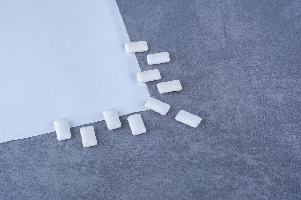 Chewing gums decoratively aligned at the edge of a piece of paper on marble surface