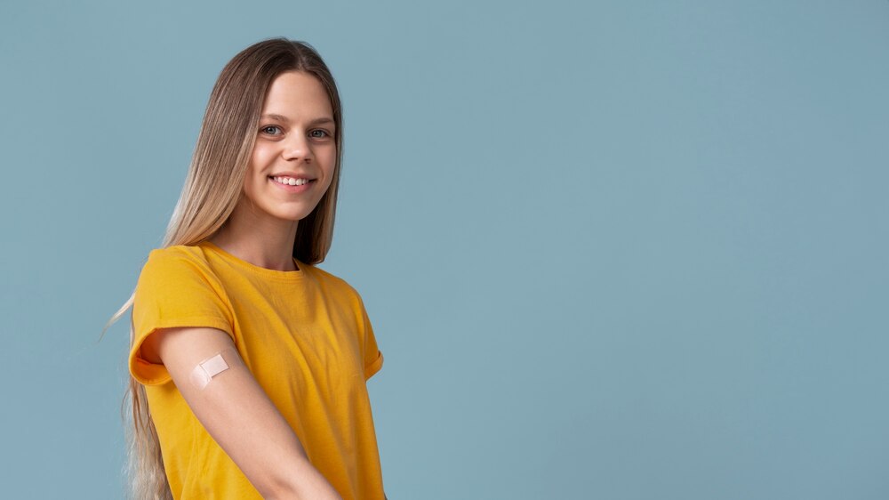 Smiley woman showing arm with sticker after getting a vaccine