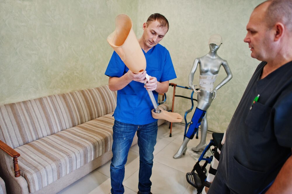 Two prosthetist man workers with prosthetic leg working in laboratory