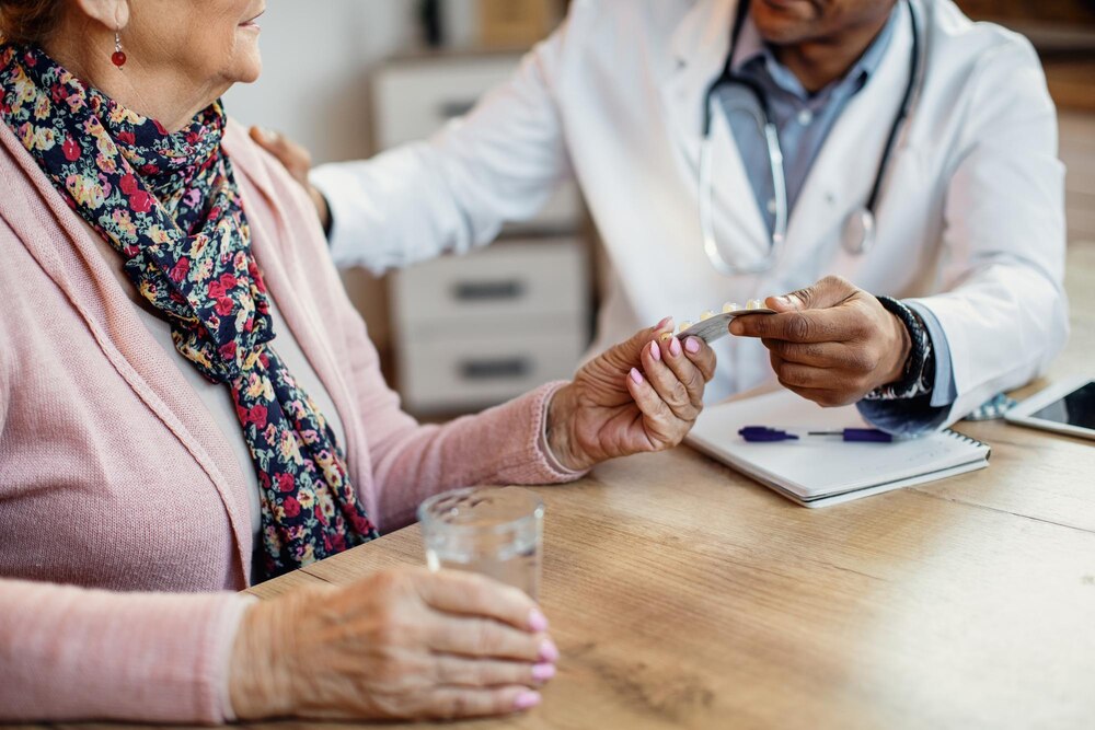 Closeup of a doctor giving pills to senior woman during home visit